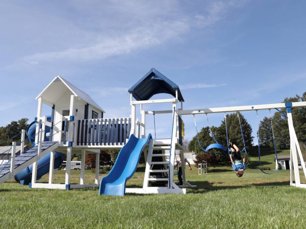 blue swing set with three swings with upside down child on swing