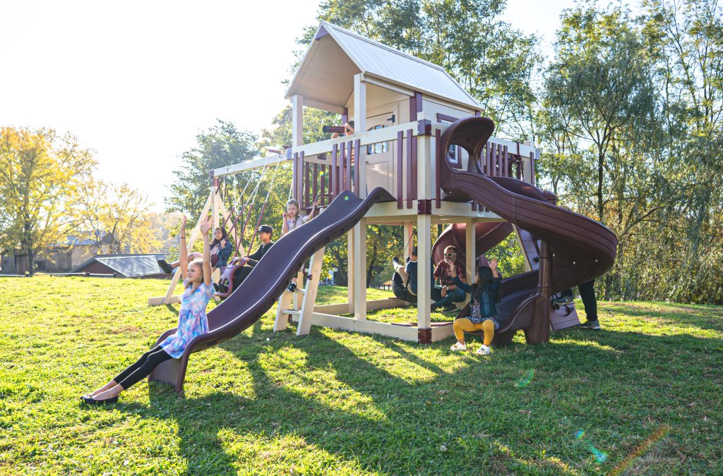 Large playhouse on a vinyl swingset with a wraparound porch