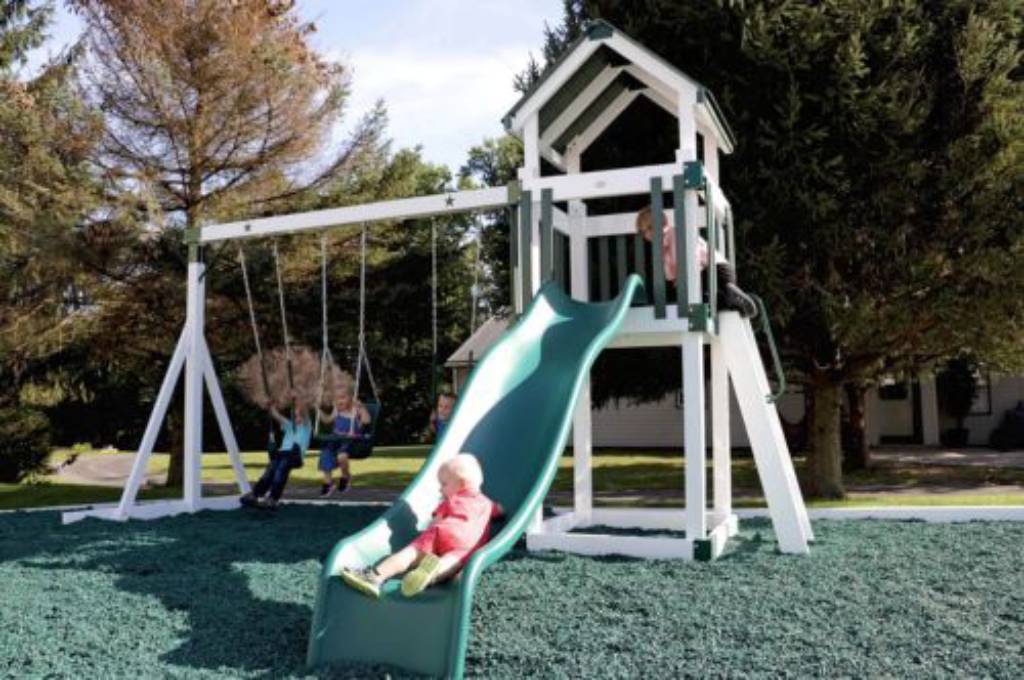 child going down the slide of playset and swing set options star cluster